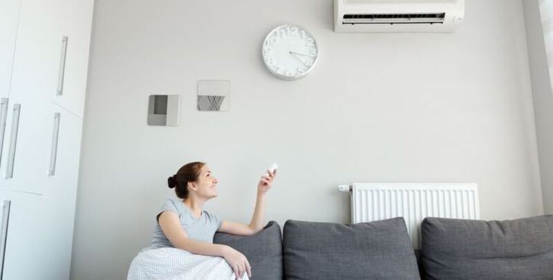 A woman adjusts the air con temperature
